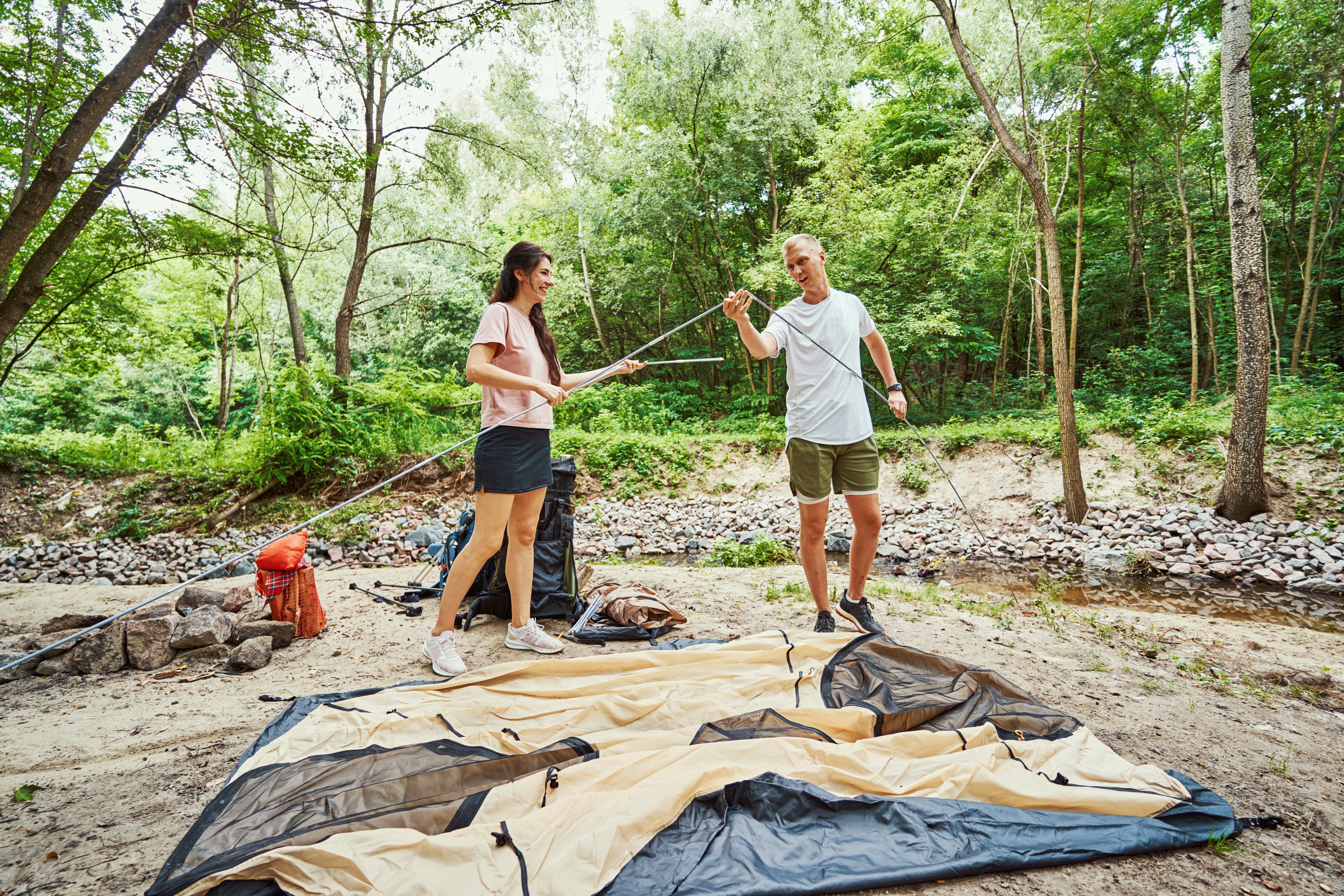 cheerful-young-couple-fixing-tent-in-wood-2024-10-18-08-37-12-utc